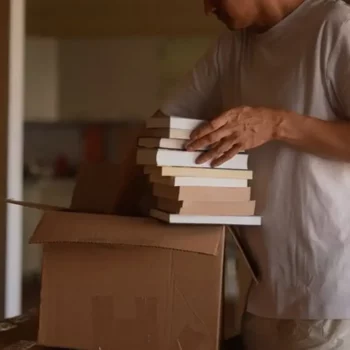 Umzugsvorgang Mann packt Buecher in den Zuegelkarton